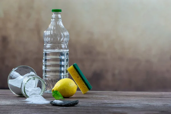 Household cleaning with baking soda, lemon, a sponge and a bottle.