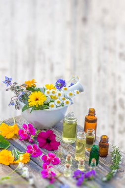 Essential oil and perfume from medicinal plant in mortar surrounded by petals