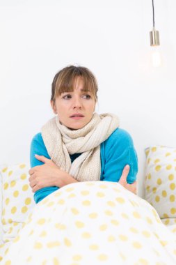 A young woman in bed suffering from a flu-like condition.