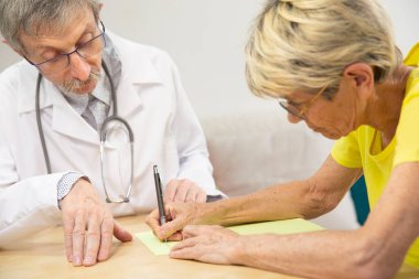 Physician doing writing rehabilitation for a woman with Parkinson's disease.