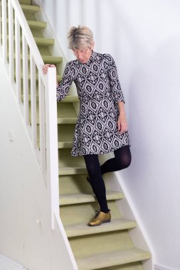 Elderly woman coming down stairs.