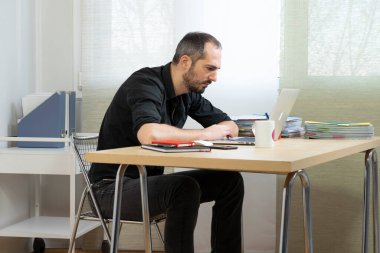 Man sitting at his desk in a bent-over position.