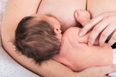 Mother breast feeding 2-week-old baby.