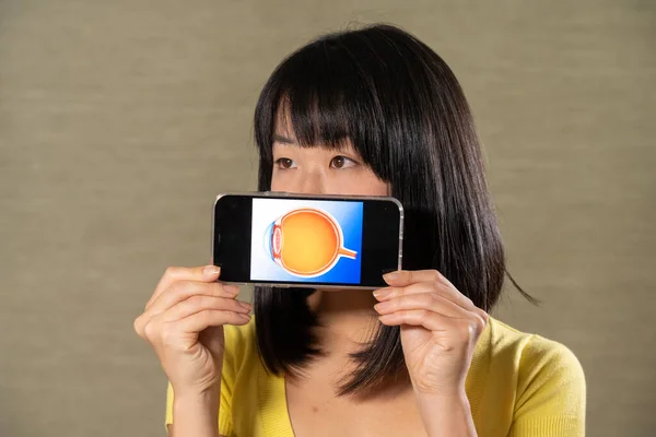 Woman holding screen with cut eye.