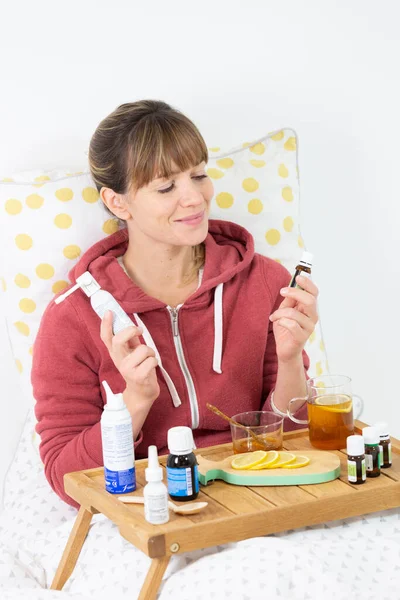 Young woman in bed hesitating between industrial medecine and natural remedies.