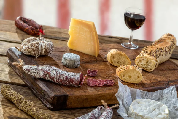 Snacks with wine - various types of cheeses, figs, nuts, honey, grapes, bread on a gray background.