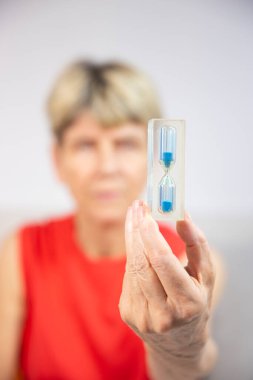 Old woman looking at an hourglass