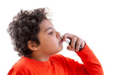 Cute teen boy spraying medicine in nose against flu