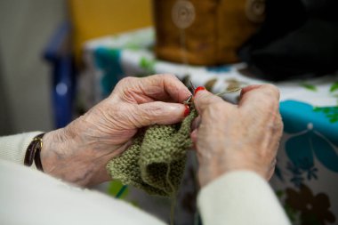 Elderly woman knitting in a retirement home.