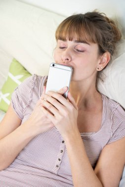 Woman worshiping her smartphone. Dependency and addiction behavior.