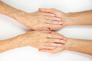 An elderly woman and young womans hands. 