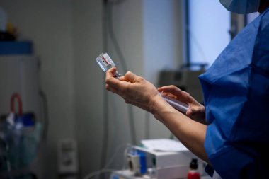 Nurse preparing adrenaline injection during cosmetic surgery.