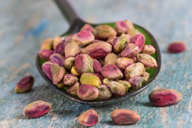 yeşil bir kaşık, izole, ahşap arka plan içinde soyulmuş Antep fındık