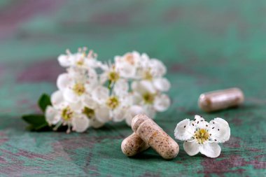 Capsule of food supplements and white flowers.