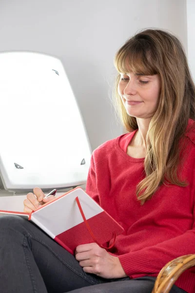 Woman Sitting Her Diary Light Therapy Lamp — Stok fotoğraf