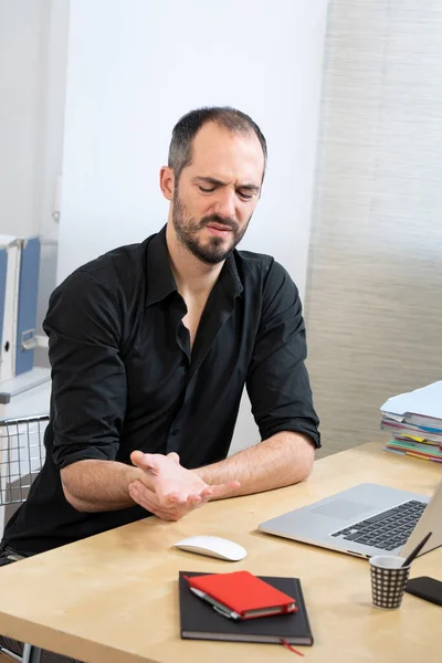 A man at his desk with hand and wrist pain.