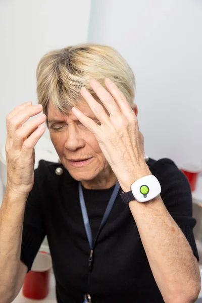 Elderly woman with a medical alert system around her wrist.