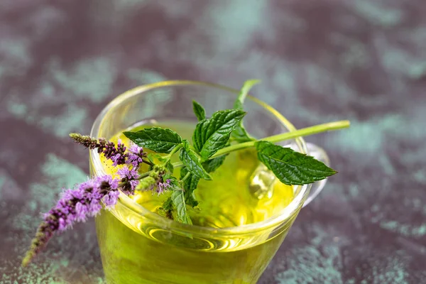 Close-up of a sprig of mint on top of a glass cup.