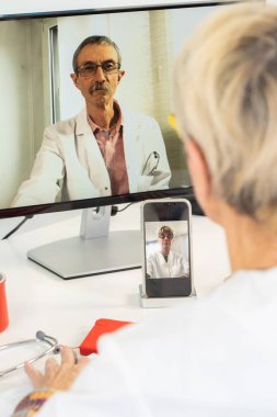 Close-up of a teleconsultation between two doctors, one of whom is filmed with his phone.