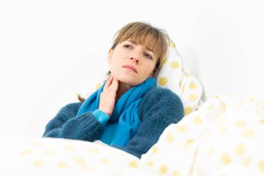 A young woman in bed suffering from a flu-like condition.