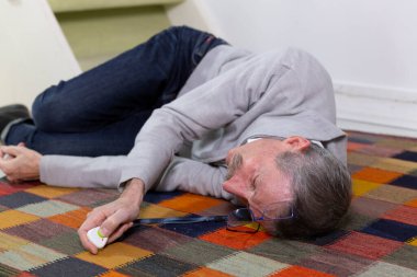 Elderly man with a medical alert system who has fainted and fallen down stairs.