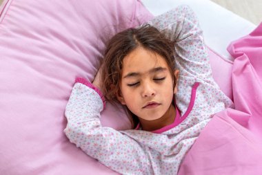 Uyuyan güzel. Elinde t ile uzanmış güzel bir kız. 10 yıl uyuyan kızın yakın plan portresi. Şirin. Pastel tonlarda çocuk portresi. Üst görünüm.