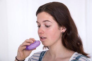 Girl using asthma medication. clipart
