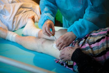 A nurse gives a patient with pressure ulcers an intramuscular injection of the vitamin.
