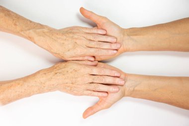 An elderly woman and young womans hands. 