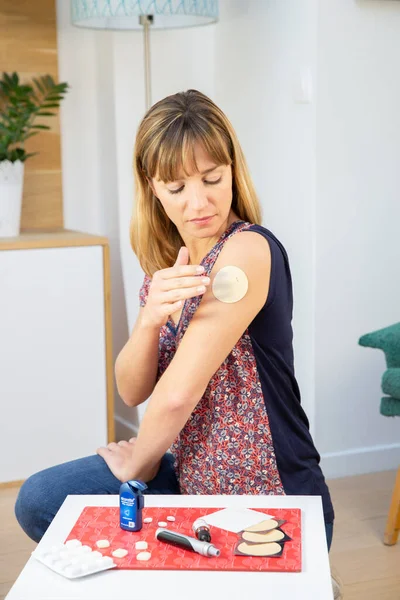 A woman applying a nicotine patch to stop smoking.