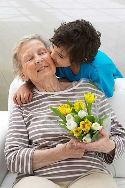 Boy offering flowers to his grandmother.
