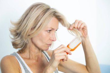 Woman looking at her split ends.