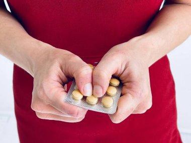 Hands holding a glass of water and a pill.