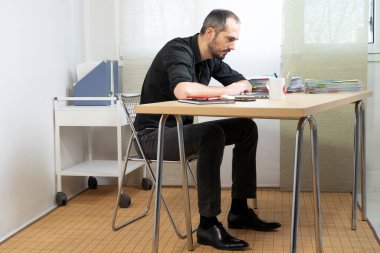 Man sitting at his desk in a bent-over position.