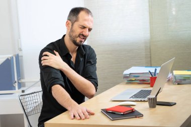 A man at his desk with shoulder pain.