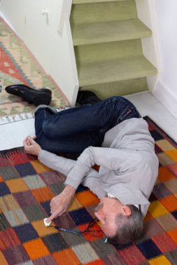 Elderly man with a medical alert system who has fainted and fallen down stairs.