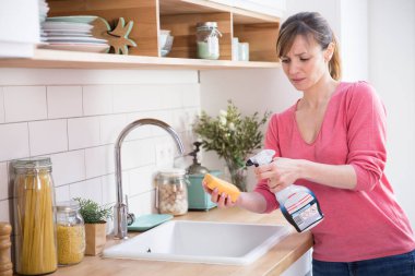 Woman using a conventional cleaning product.