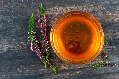 A saucer full of heather honey and a sprig of heather.