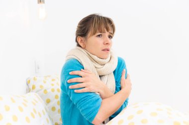 A young woman in bed suffering from a flu-like condition.
