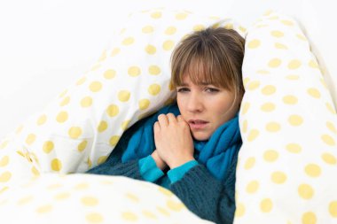 A young woman in bed suffering from a flu-like condition.