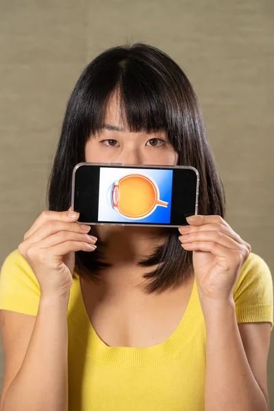 Woman holding screen with cut eye.