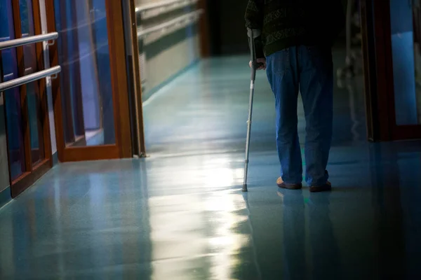Elderly man with his cane in a hallway of a retirement home.