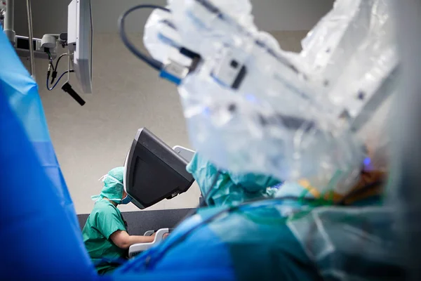 In the operating room, a hysterectomy with a surgical robot controlled from a console.