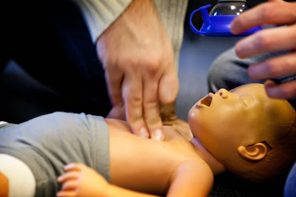 First aid training: cardiac massage on an infant dummy.