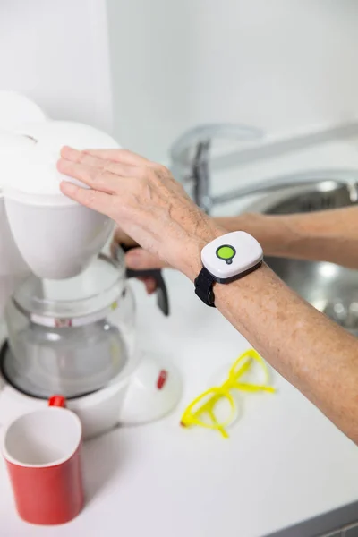 Elderly woman with a medical alert system around her wrist.