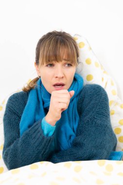 A young woman in bed suffering from a flu-like condition.