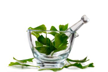 Ginkgo biloba leaves in a glass mortar on a white background.