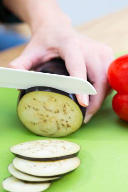 A young woman in her kitchen who has cut herself with a kitchen knife.