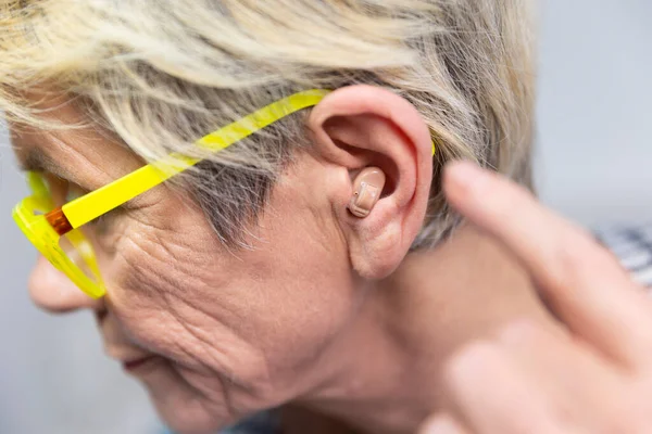 Woman Placing Hearing Aid Her Ear — 스톡 사진