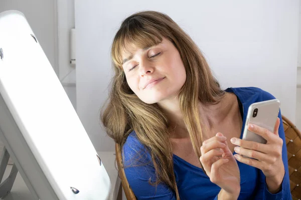 Woman Sitting Her Smartphone Light Therapy Lamp — Stok fotoğraf